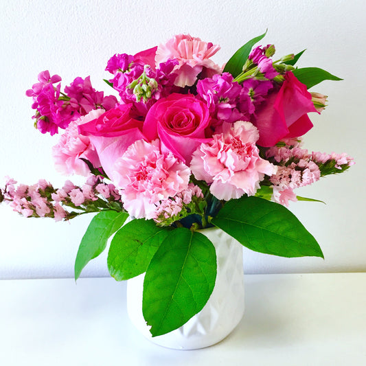 Bouquet of pink and green flowers in a white vase on a white background for flower delivery in Miami