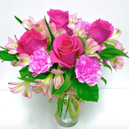 Bouquet of pink flowers in a clear vase on a white background for flower delivery in Coral Gables Miami