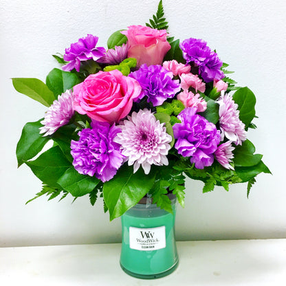 Bouquet of pink and purple flowers in a green candle holder on a white background in Miami flower shop