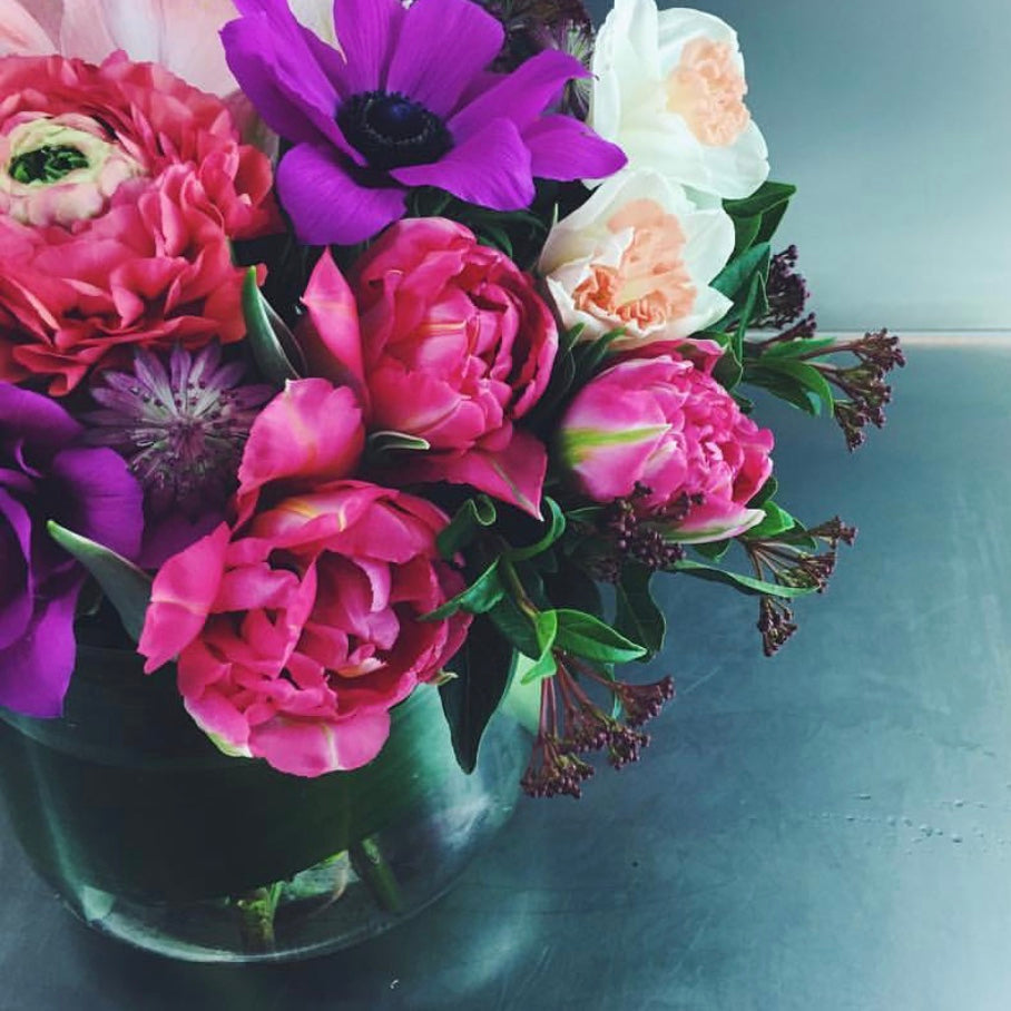 Bouquet of colorful flowers in a clear vase on a reflective surface from the best miami flower shop for delivery