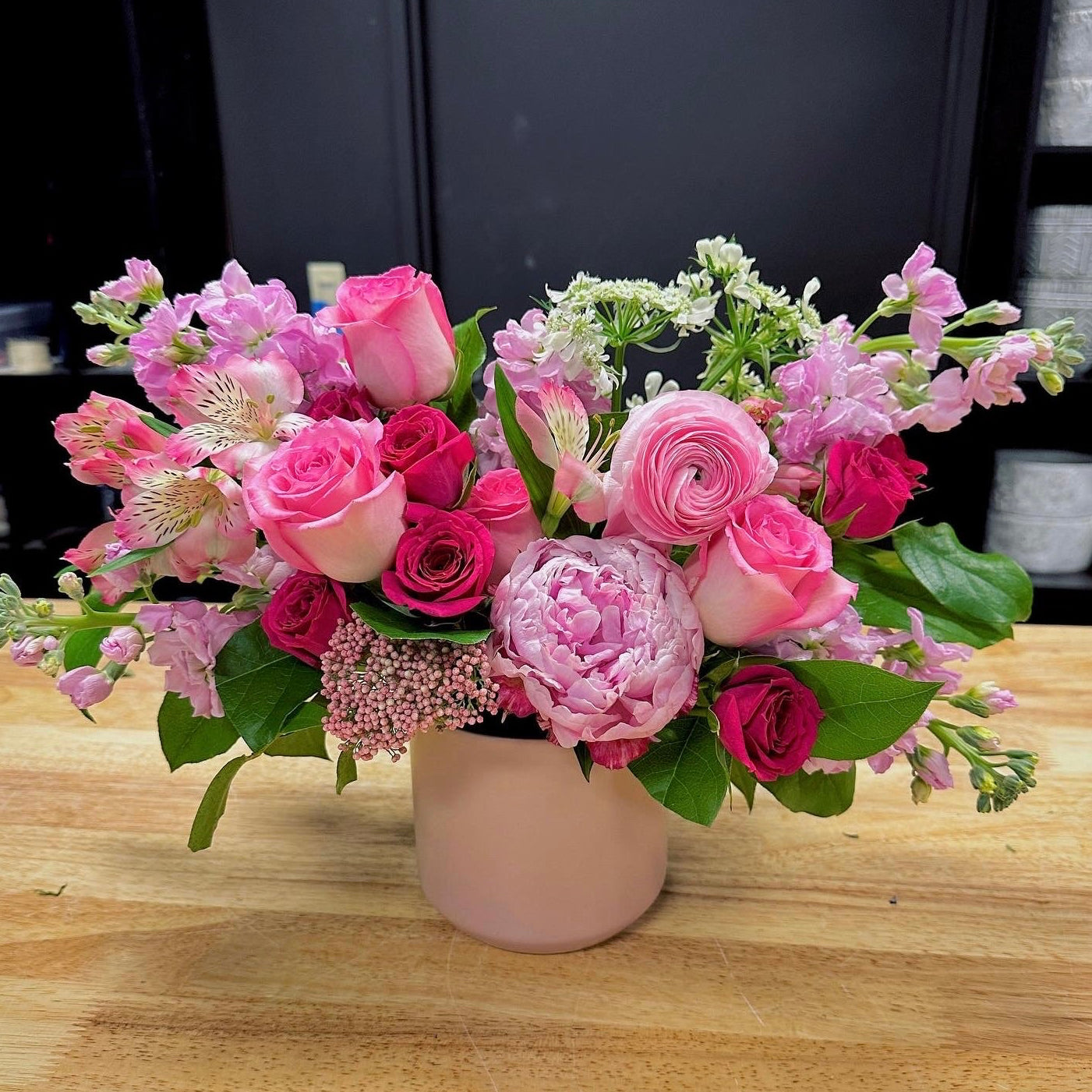 Bouquet of pink flowers in a vase on a wooden table send flowers