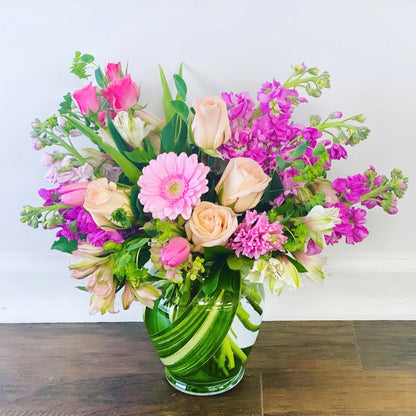 Bouquet of flowers in a green vase on a wooden surface with a white background