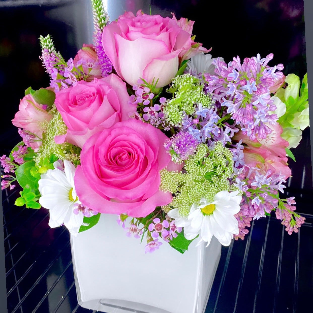 Bouquet of pink and white flowers in a white container on a dark background from Hialeah florist
