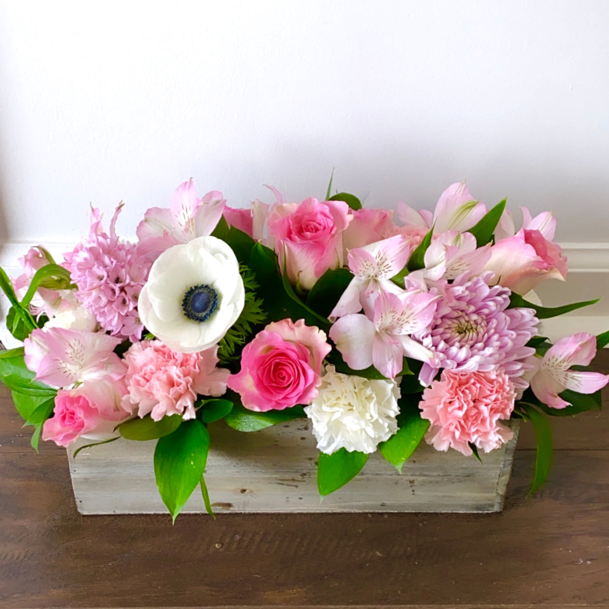 Floral arrangement in a wooden box on a wooden surface with a white background for flower delivery in Medley Florida