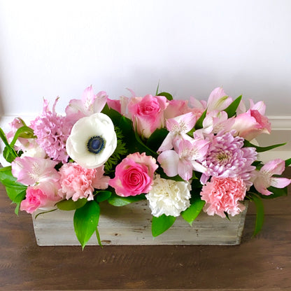Floral arrangement in a wooden box on a wooden surface with a white background for flower delivery in Medley Florida