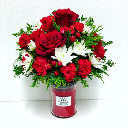 Bouquet of red and white flowers in a WoodWick candle container on a white background