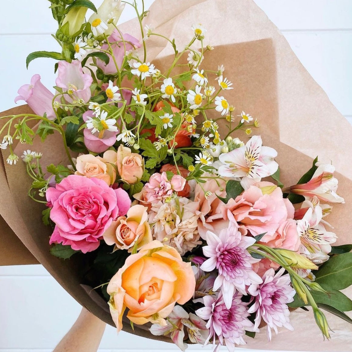 Bouquet of flowers wrapped in brown paper on a white background from Miami flower shop