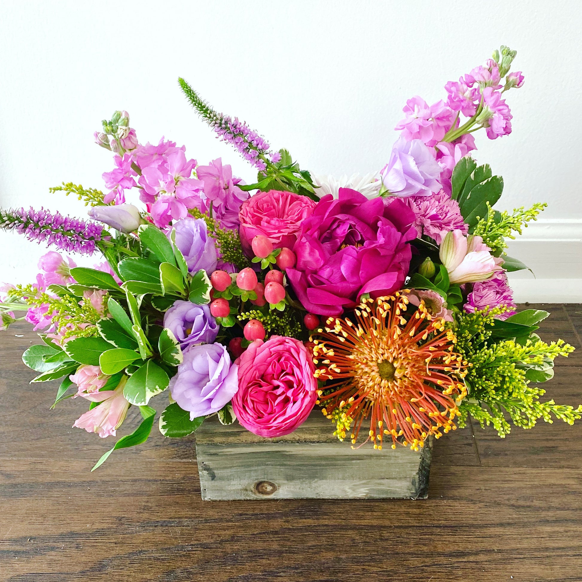 Colorful arrangement of flowers in wood box with peonies and unique blooms.  Same day flower delivery in Miami Beach
