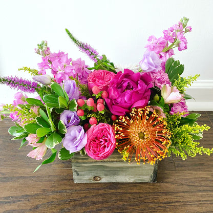 Colorful arrangement of flowers in wood box with peonies and unique blooms.  Same day flower delivery in Miami Beach