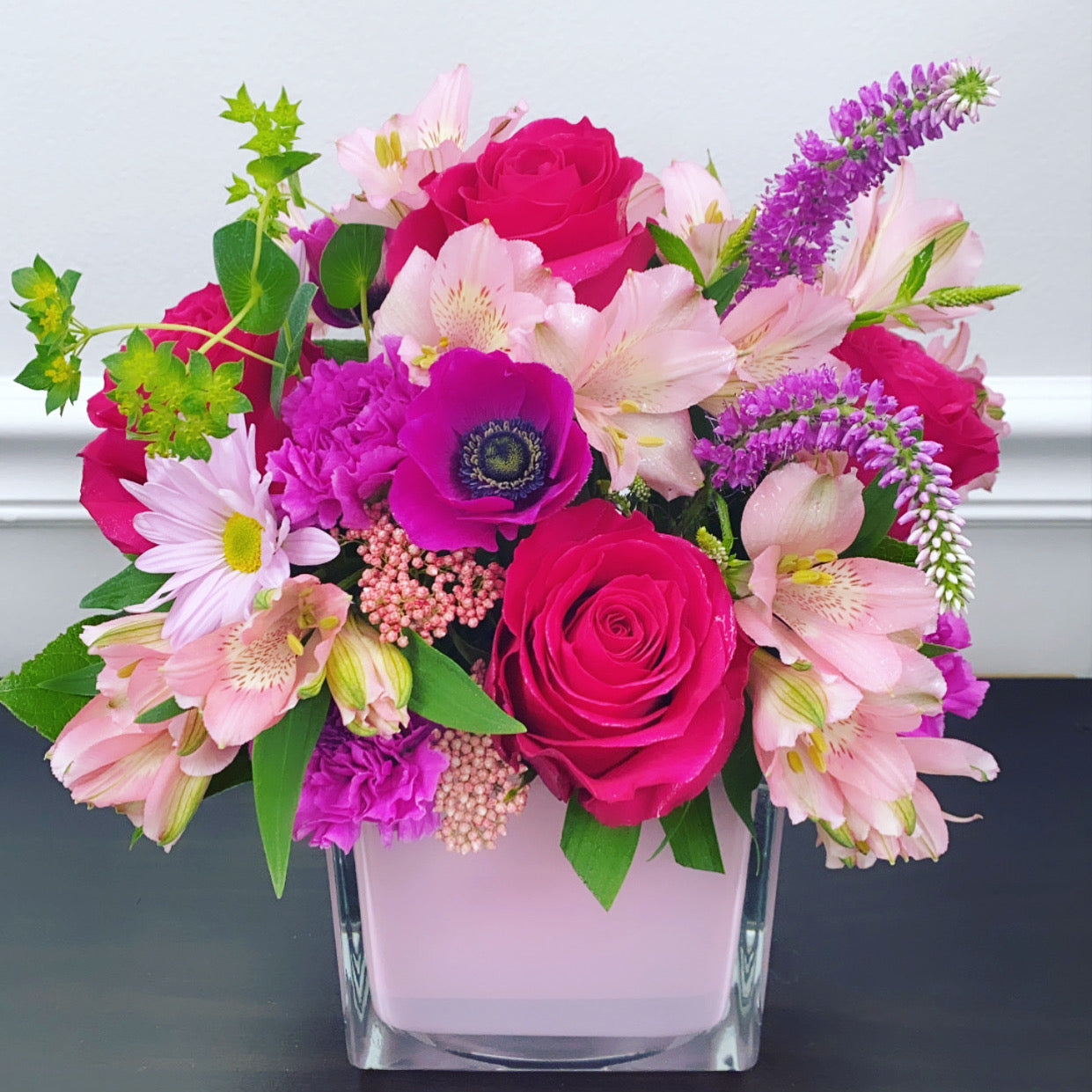 Bouquet of colorful flowers in a clear vase on a neutral background for flower delivery in Hialeah