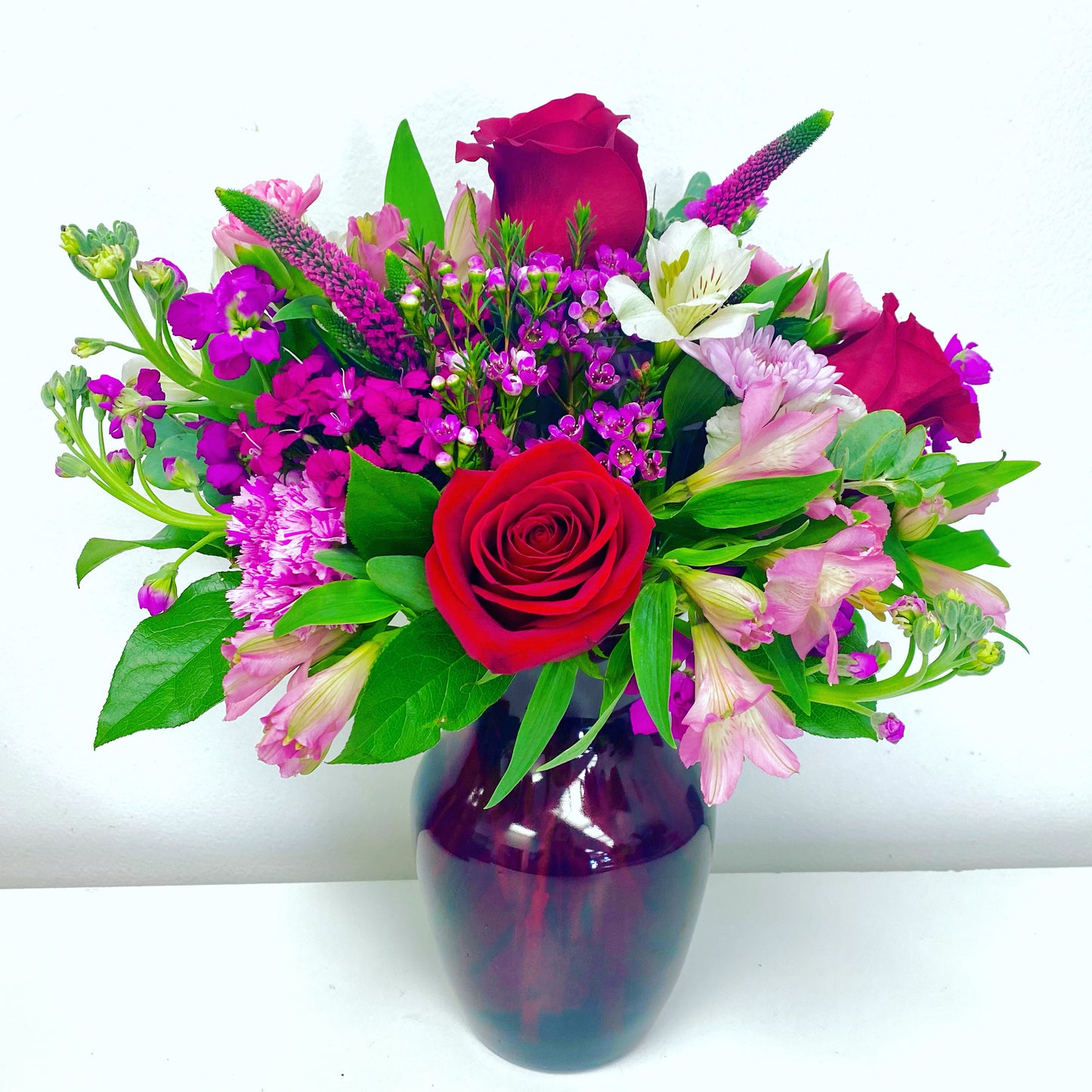 Bouquet of colorful flowers in a purple vase on a white background for Valentines day and anniversary in Miami from flower shop