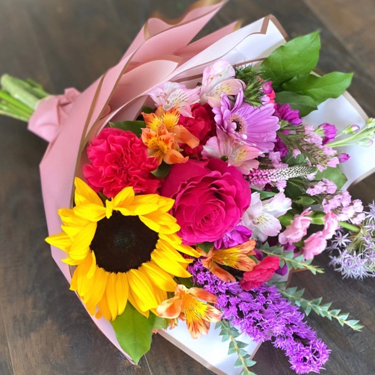 Bouquet of colorful flowers with a yellow sunflower on a wooden surface Pembroke Pines florist